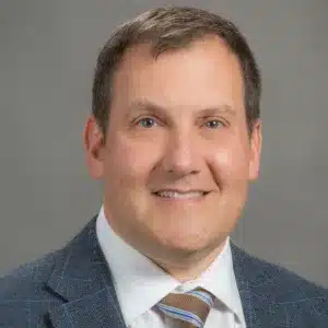 Photo of Dr. Robert Sweet. He is wearing a grey suit with a white dress shirt.